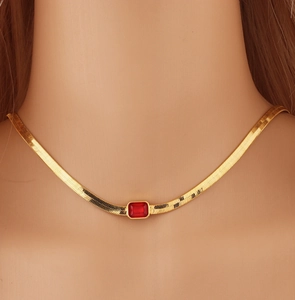 Dettaglio della collana a serpente placcata oro 18k con gemma rossa su una modella