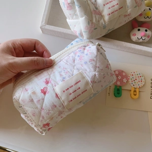 Détail de la trousse de maquillage matelassée à fleurs tenue à la main pour la taille