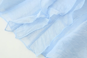 Close-up of light blue layered chiffon fabric with detailed ruffle edges and stitching