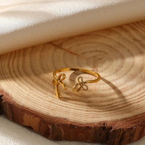 Detailed macro shot of a golden bow-shaped ring on a wooden surface with silk backdrop