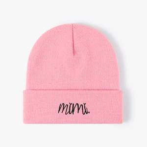 Detail of pink knitted beanie featuring black cursive mimi embroidery on the folded cuff