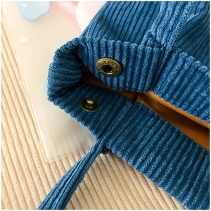 Detail of blue corduroy bag with yellow lining and engraved metal snap button