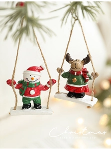 Christmas resin ornament with snowman and reindeer on a swing in festive settings