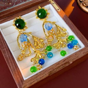 Detail von Vintage-Ohrringen mit grünen und blauen Perlen in einer hölzernen Schmuckbox