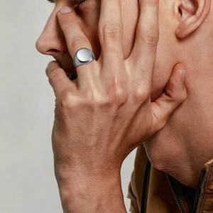 Minimalist men's round signet ring in polished stainless steel worn by a male model