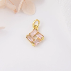 Macro view of gold plated square pendant with four baguette-cut pink zircon stones for DIY