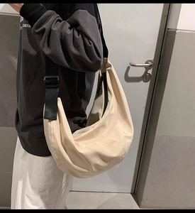 Close-up of beige nylon crossbody bag with adjustable wide black shoulder strap