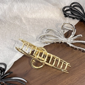 Detail of elegant gold and silver metal hair claws with bow and geometric designs