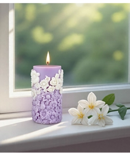Detailed relief of white flowers on a purple cylindrical scented candle lit by a window