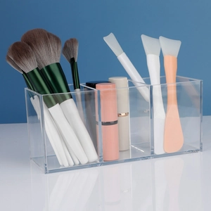 Three-slot clear acrylic cosmetic organizer holding makeup brushes and lipsticks