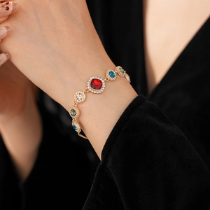 Close-up of a gold bracelet with red, blue, and green multi-color crystals on a wrist