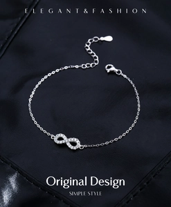 Detail of silver S925 moissanite bracelet with infinity symbol on black leather background