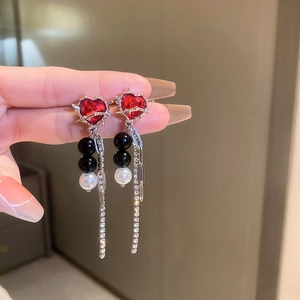 Macro shot of long tassel heart earrings with red gemstone and black and white beads