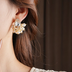 Close-up of a teardrop crystal and cluster pearl earring on a model's ear
