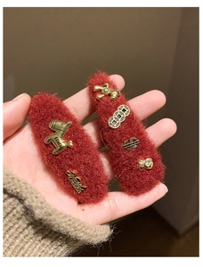 Detail of red plush hair clip with golden charms like pony and money bag for New Year