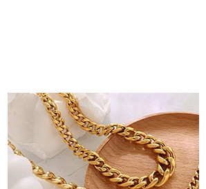 Detail of chunky gold Cuban chain necklace on white stone and wooden tray display