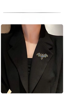 Gothic bat brooch with blue rhinestones displayed on a black blazer lapel