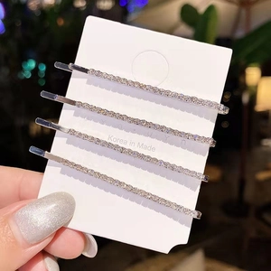 Close-up of four silver alloy hair clips with sparkling white rhinestones on card