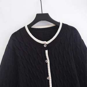 Chic black cable knit cardigan with white contrast piping and button front closure