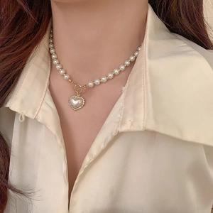 Close-up of pearl necklace with heart pendant and gold OT toggle clasp on model