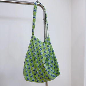 Detail of floral cotton tote bag in green with blue flowers on metal hanger