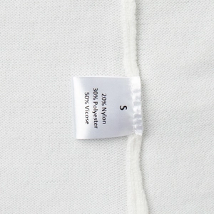 Detail of size S garment label showing 50% viscose fabric composition on white knitwear