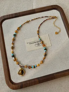 Detailed view of Tiger Eye teardrop pendant necklace on beige linen lining