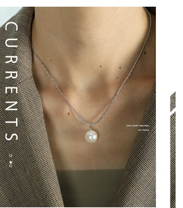 Close-up of a lustrous round pearl pendant on a delicate silver snake chain necklace