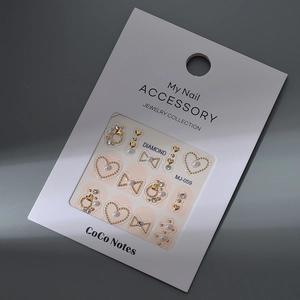 Close-up of golden bow and heart nail charms set with pearls and rhinestones