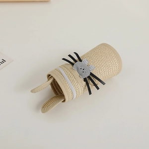 Détail de la texture en paille et du chat de dessin animé 3D sur le chapeau enfant