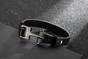 Détail du bracelet en cuir tressé marron foncé avec fermoir en métal noir poli en H