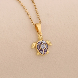 Detail of a turtle pendant necklace with gold finish and purple shell inlay