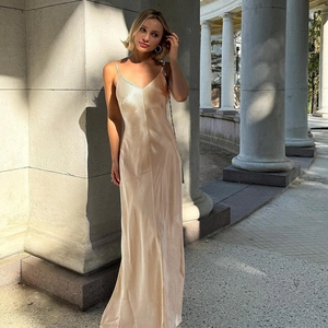 Détail de la texture satinée champagne élégante et du drapé de cette robe longue maxi