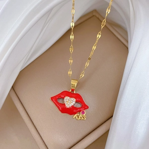 Detailed close-up of a gold necklace featuring red lips and a sparkling pavé heart pendant