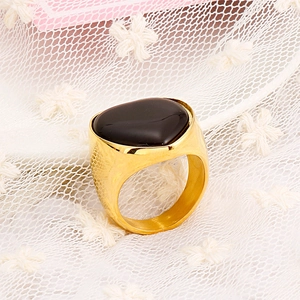 Golden stainless steel heart ring with black stone on white lace background