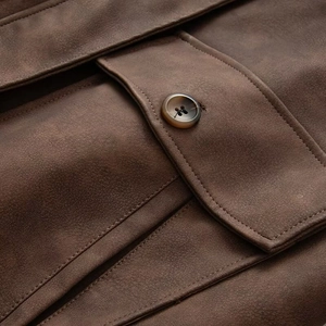 Macro shot of brown suede jacket pocket with detailed stitching and resin button