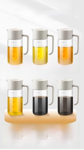 Detail view of large glass oil bottles with clear measurement scales and easy-grip handles