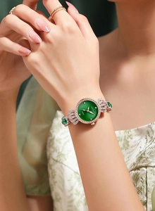 Detail of luxury rose gold watch with green dial and peacock-style gemstone wristband