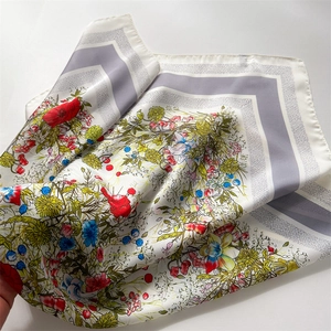 Close-up of vibrant floral patterns and silky texture on a white square scarf detail