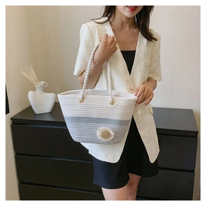 Detail of woven tote bag with 3D daisy flower and rope handle on a stylish model