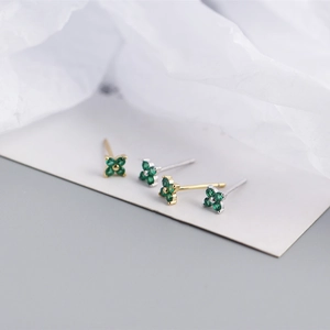 Macro view of dainty S925 silver four-leaf flower stud earrings with green zircon stones