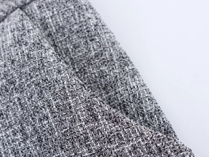 Close-up of grey tweed fabric texture with detailed woven pattern for a women's suit