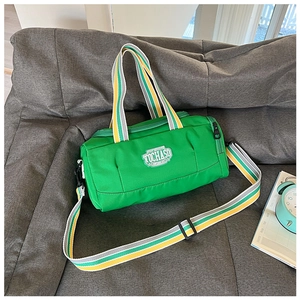 Green cylindrical sports bag with striped straps on sofa with lifestyle background