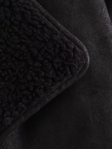 Gros plan détaillé sur la texture de la veste en suédine noire et similicuir d'agneau