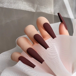 Détails des faux ongles longs ballerine bordeaux mat sur la main d'un mannequin