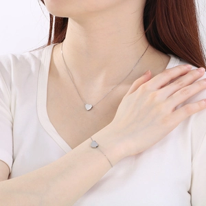 Gros plan d'un modèle portant un ensemble collier et bracelet cœur en argent poli