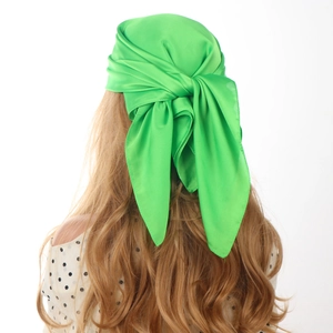 Detail of bright green satin scarf tied in wavy blonde hair with silky texture focus