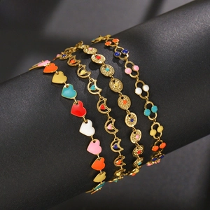 Detail of four gold bracelets with colorful enamel hearts and celestial charms on a stand
