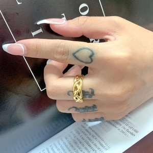 Detail of a polished gold-plated chain link ring worn on finger with tattoo and manicure