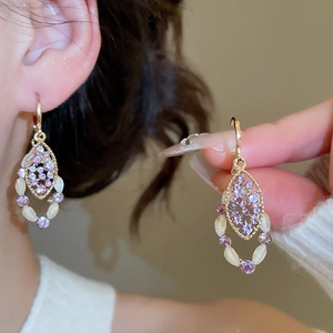 Close-up of vintage hollow water-drop earrings with purple crystals and oval opal beads